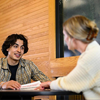 focus on male individual talking with female pointing to a piece of paper