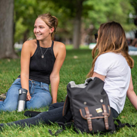 two individuals sitting on grass chatting