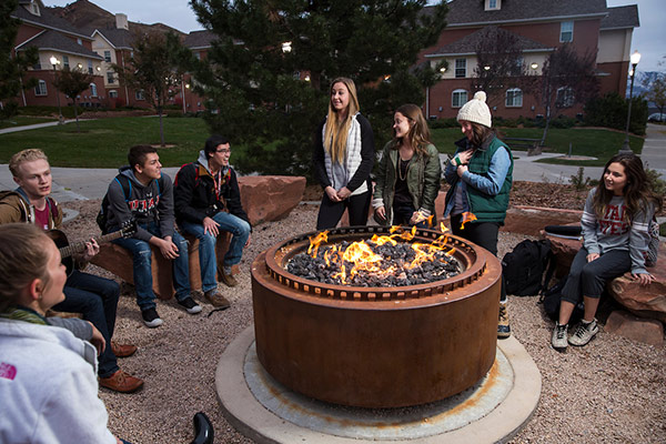 group of students talking around a campfire near the dorms