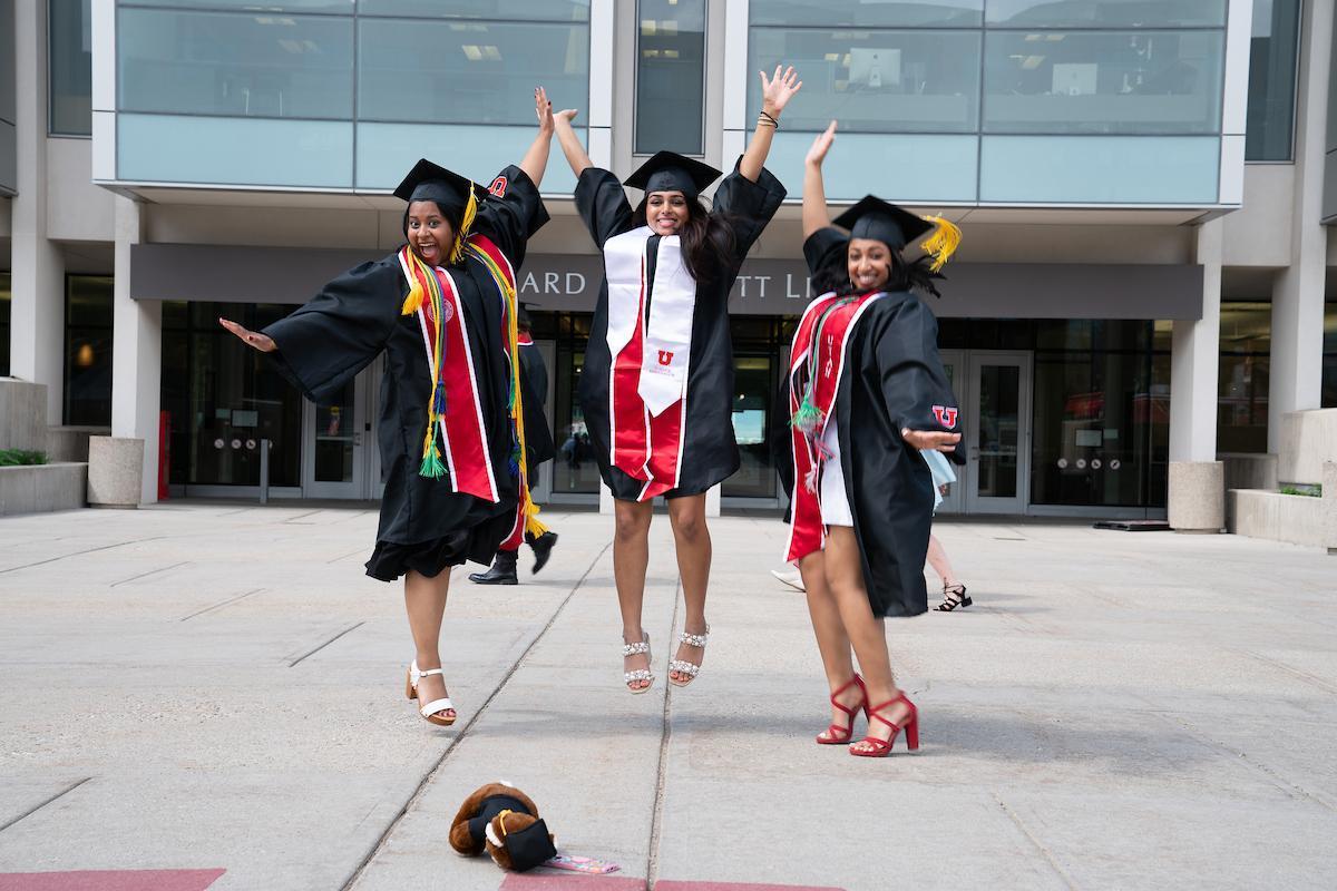 Three people jumping with joy in graduation gear