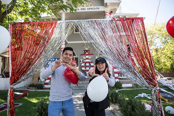 two individuals standing outside of a house on greek row decorated for homecoming