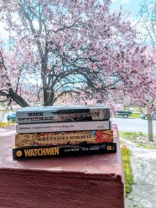 cooper's stack of books in front of a tree