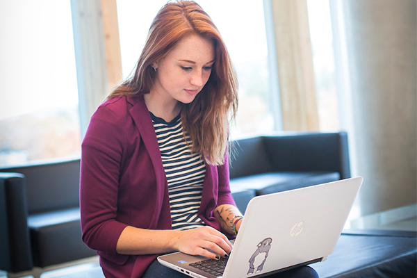 individual sitting near window typing on laptop