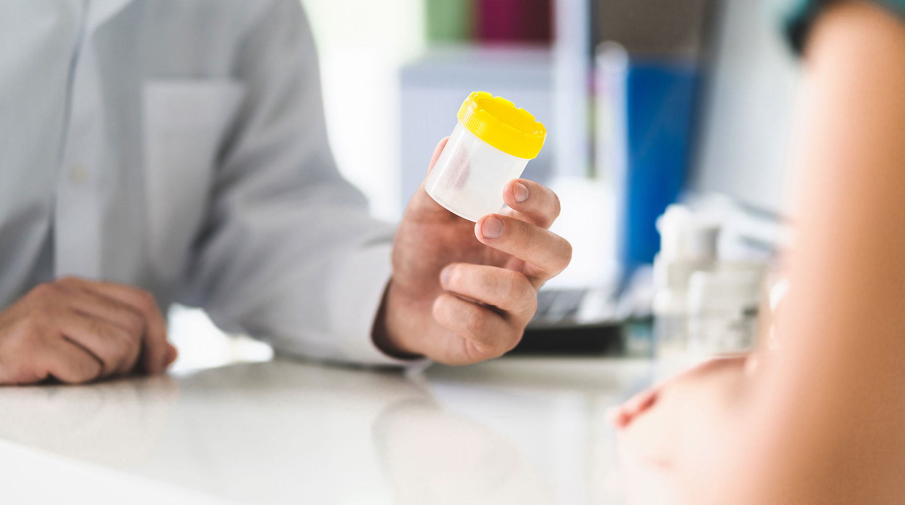 A person holding a urine sample cup