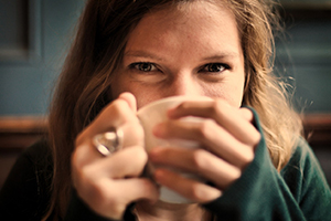 female individual sipping a drink out of a mug