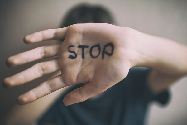 blurred person with focus on hand that says "stop"