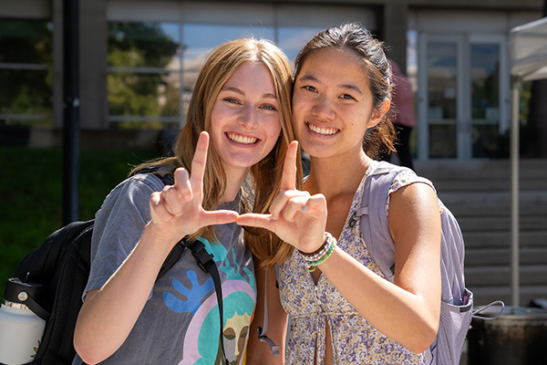 two females using their fingers to make a block u