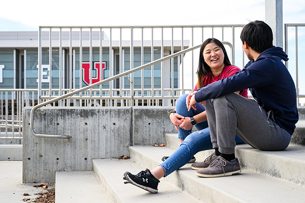 male and female individuals sitting on stairs with library in the background